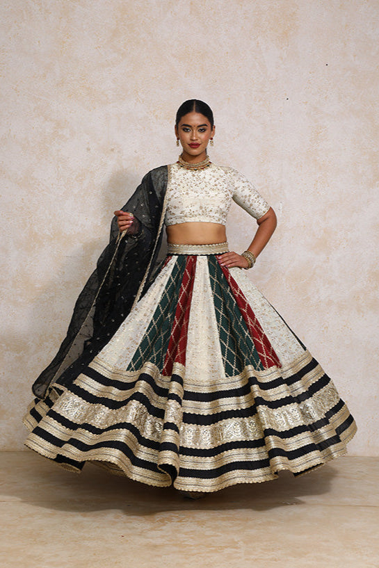 Woman wearing a traditional outfit with a white blouse and a long, patterned skirt on a plain background